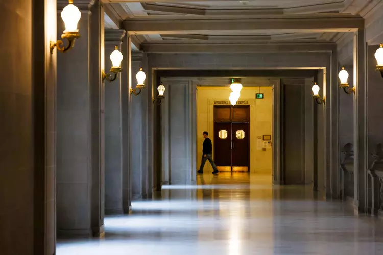 A person walks through a empty hallway in San Francisco City Hall. The City’s Drug Crisis Commission has not held a meeting in months.